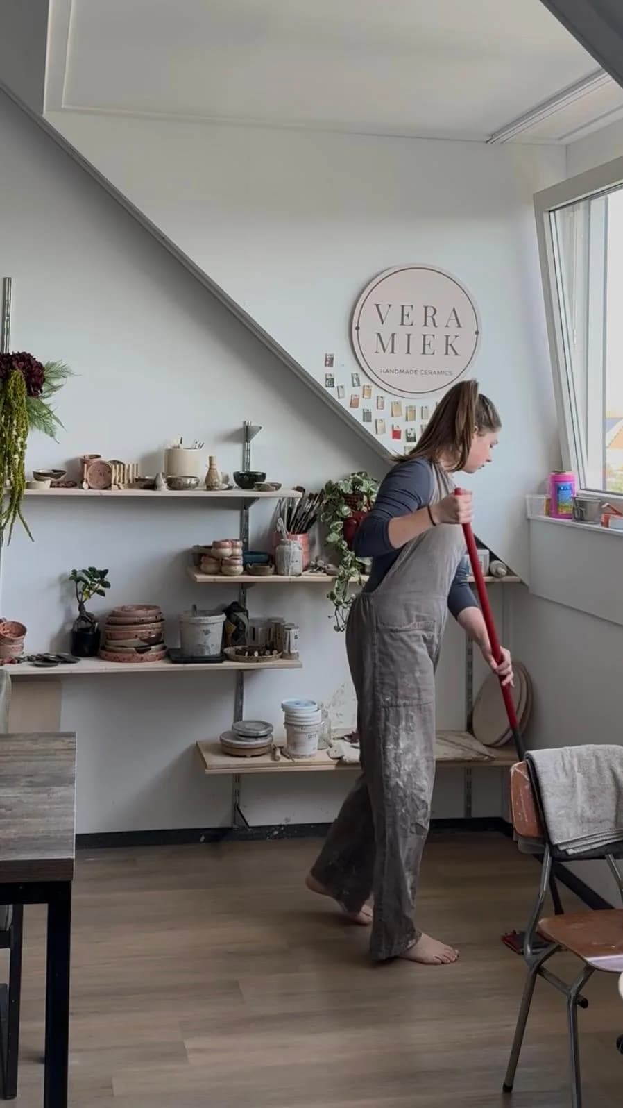 Vera aan het werk in haar atelier, met haar logo aan de muur